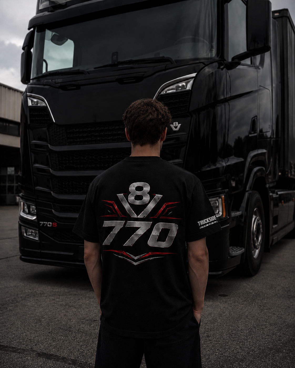 Ragazzo con T-shirt V8 770 davanti a un camion nero